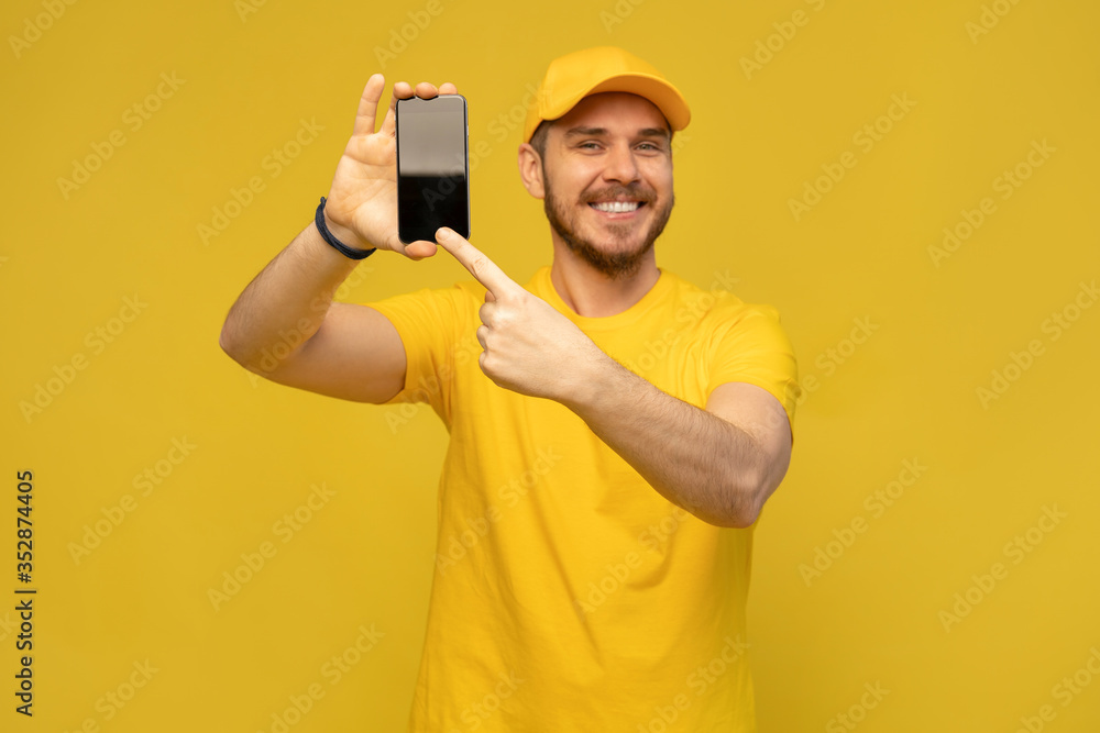 Portrait of a excited happy young delivery man in yellow cap standing isolated over white background Portrait of a excited happy young delivery man in yellow cap standing isolated over white background