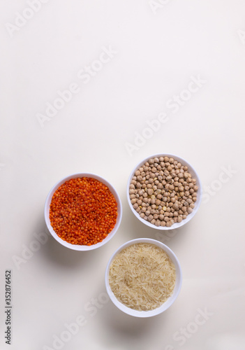 Rice, lentils, chickpeas in white bowls on a light yellow background. Healthy food concept. Top view.