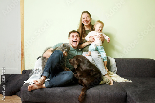 Young happy family with little toddler kid and pets dog and cat at home on the couch © dariazu