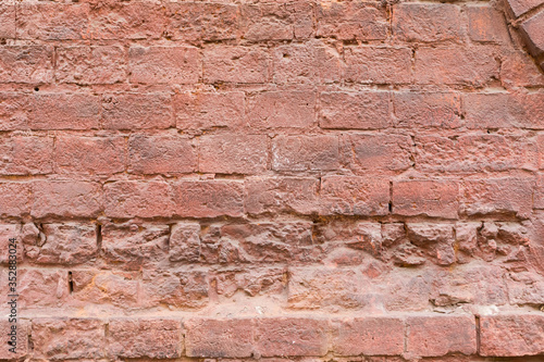 Background Old brick wall of the building with decor elements in the view of cracked bricks of red color