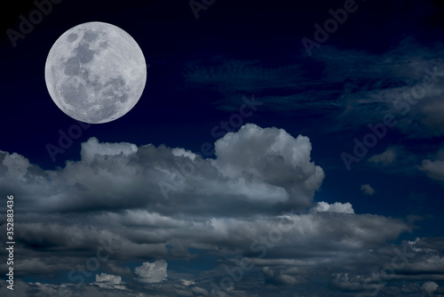 Full moon over clouds on the sky.