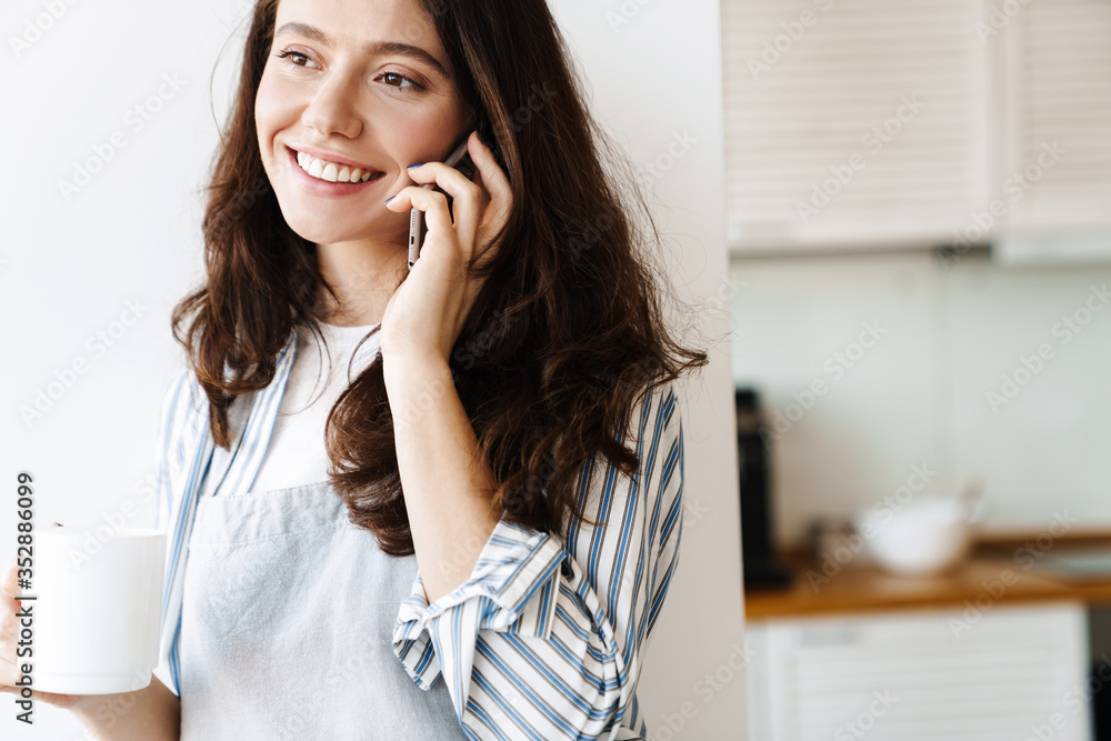 Image of happy woman talking on cellphone while drinking coffee Image of happy woman talking on cellphone while drinking coffee