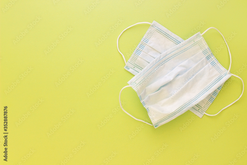 Two used medical white masks on a bright yellow background Two used medical white masks on a bright yellow background