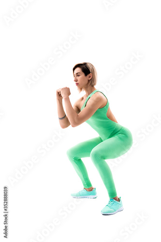 Studio shot of an athletic woman doing squats isolated over white background.