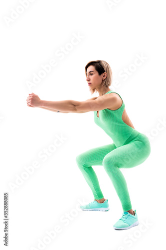 Studio shot of an athletic woman doing squats isolated over white background.