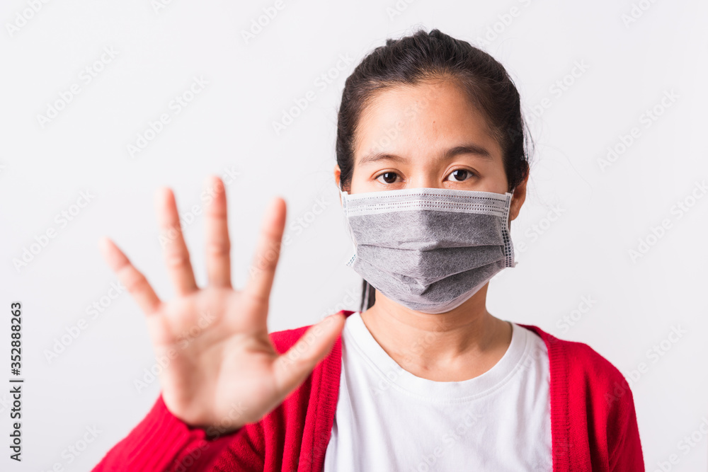 Asian adult woman wearing red shirt and face mask protective against coronavirus or COVID-19 virus or filter dust, air pollution her raise palm hand to no or stop sign, isolated white background Asian adult woman wearing red shirt and face mask protective against coronavirus or COVID-19 virus or filter dust, air pollution her raise palm hand to no or stop sign, isolated white background