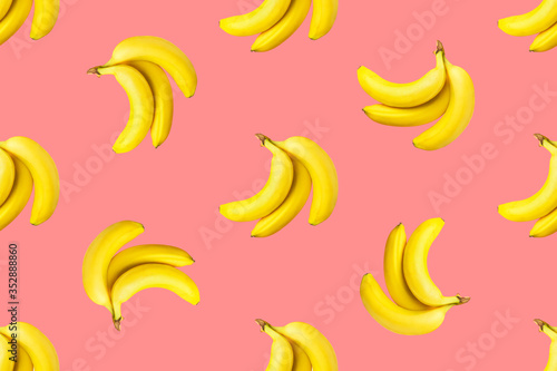 Fototapeta Naklejka Na Ścianę i Meble -  Seamless pattern from bundles of ripe yellow bananas on pink background. Tropical summer fruits concept. Template for wallpaper textile print product surface design