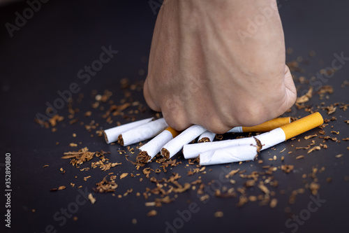 Male hand destroying cigarettes on black background.stop smoking concept. world no tobacco day