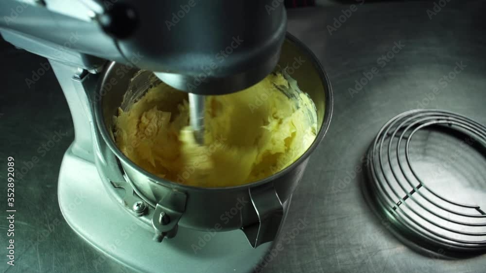 Close-up of a mixer kneads butter in a cream for making a cake Close-up of a mixer kneads butter in a cream for making a cake