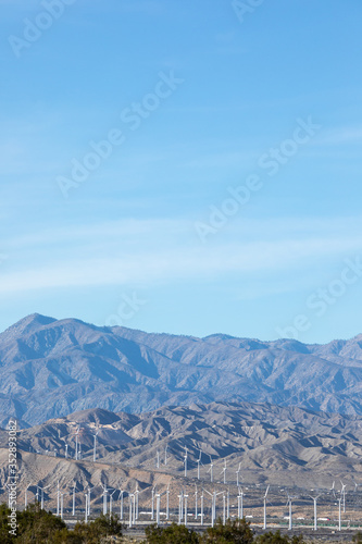Landscape of windmills at the base of desert mountains, with space for text on top © Peter