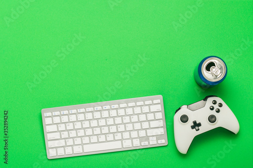 Keyboard, can with a drink and a gamepad on a green background. The concept of the game on the console, games online. Flat lay, top view. photo