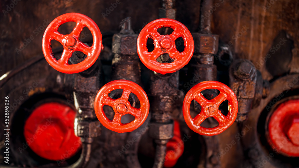 Fototapeta premium Closeup photo of red painted vavles and black pipes of vintage high pressure system on factory