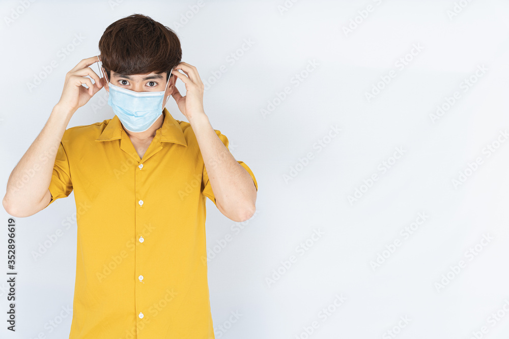 Asian handsome happy hipster man wearing a medical protection face mask for protect the coronavirus, filter dust PM 2.5 and cold on white background Asian handsome happy hipster man wearing a medical protection face mask for protect the coronavirus, filter dust PM 2.5 and cold on white background