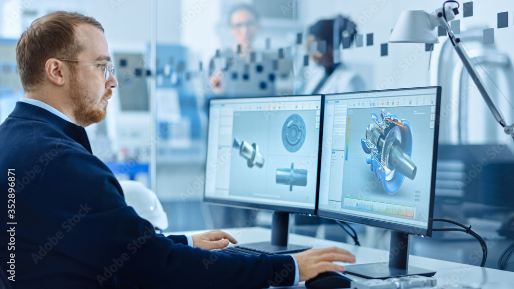 Heavy Industry Engineer Working on Personal Computer, Screen Shows CAD Software with 3D Prototype of Zero-Emissions Engine. Industrial Factory with High-Tech CNC Machinery. Heavy Industry Engineer Working on Personal Computer, Screen Shows CAD Software with 3D Prototype of Zero-Emissions Engine. Industrial Factory with High-Tech CNC Machinery.