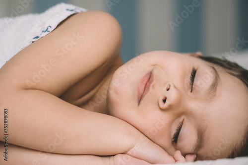 adorable boy smiling while slipping in bed