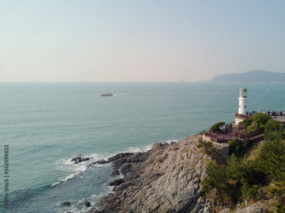 a lighthouse on a rock in Busan photographed from the drone