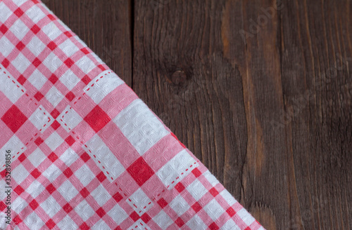 A red checked towel on a dark wooden table. Top view with a copy of the space.
