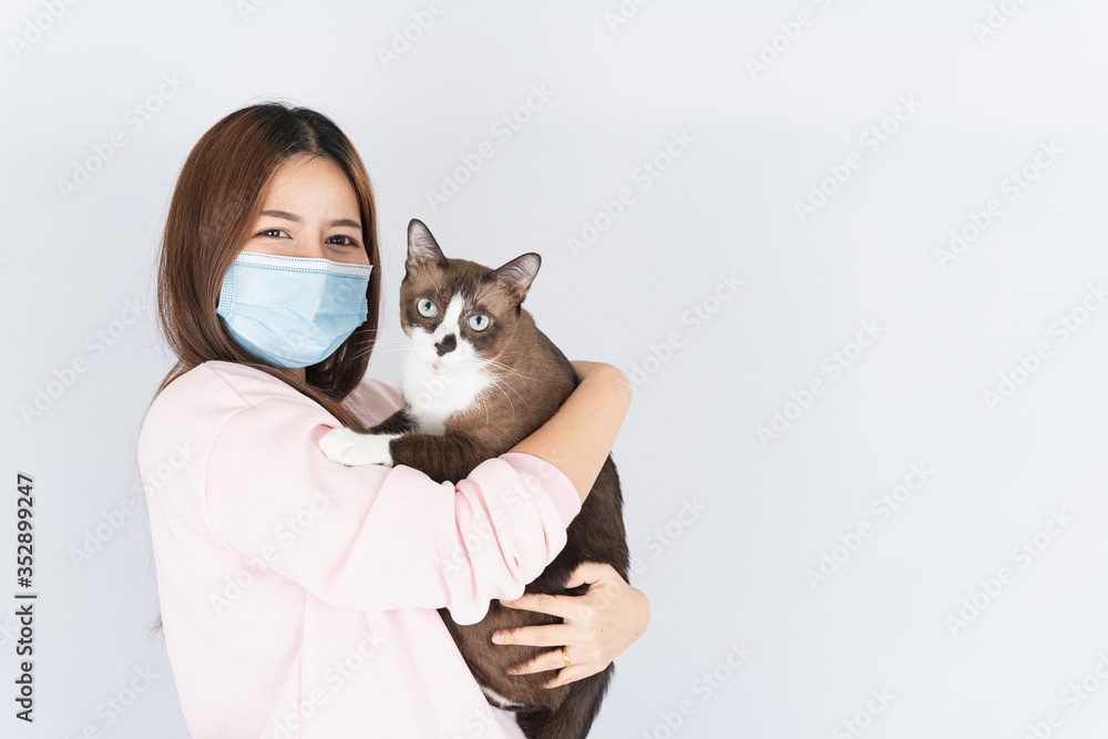 Asian beautiful happy woman wearing a medical protection face mask for protect the coronavirus, filter dust PM 2.5, cold and allergic to cat fur and she carry a cat on the white background Asian beautiful happy woman wearing a medical protection face mask for protect the coronavirus, filter dust PM 2.5, cold and allergic to cat fur and she carry a cat on the white background