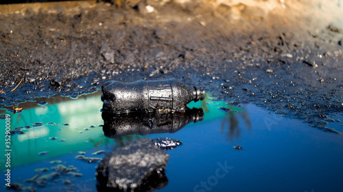 Fotografie Closeup image of soil polluted with plastic gardage and oil waste