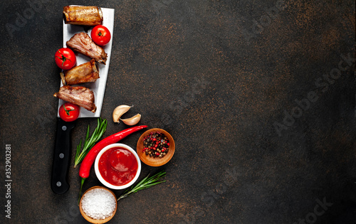 Fototapeta Naklejka Na Ścianę i Meble -  Grilled pork ribs over meat knife with spices on a stone background with copy space for your text