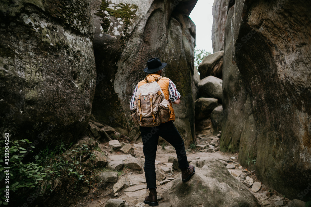 man hiker with a backpack climbs into the mountains by a rocky gorge. Travel concept