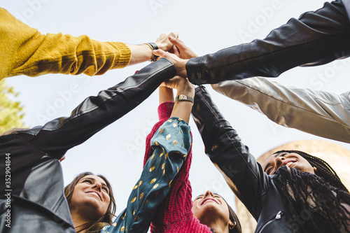 Multi-ethnic group of people holding hands together. Success, teamwork, cooperation, trust, and friendship lifestyle concept. Bottom view.