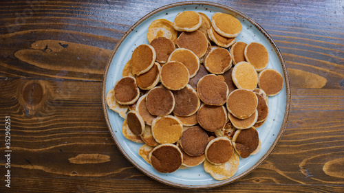Freshly baked a plate of poffertjes, traditional Dutch Mini Pancakes without any other ingredients with the wooden background