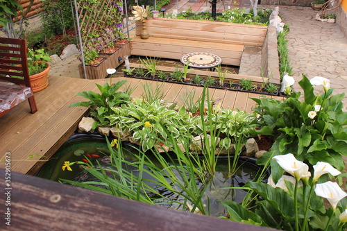 Scene with outdoor pond and patio. Garden lounge