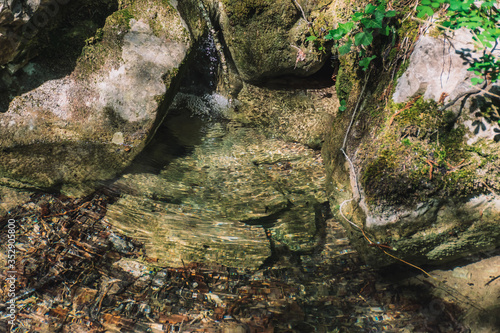 Water running down between boulders in a weak stream in a forest in the French Alps mountains