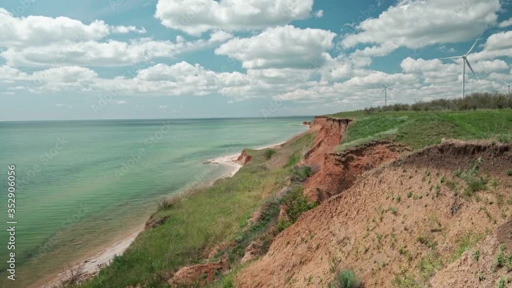 Giant Coastal Wind Turbine and Farm on a sunny Coastline For Power Generation and Clean Energy Giant Coastal Wind Turbine and Farm on a sunny Coastline For Power Generation and Clean Energy