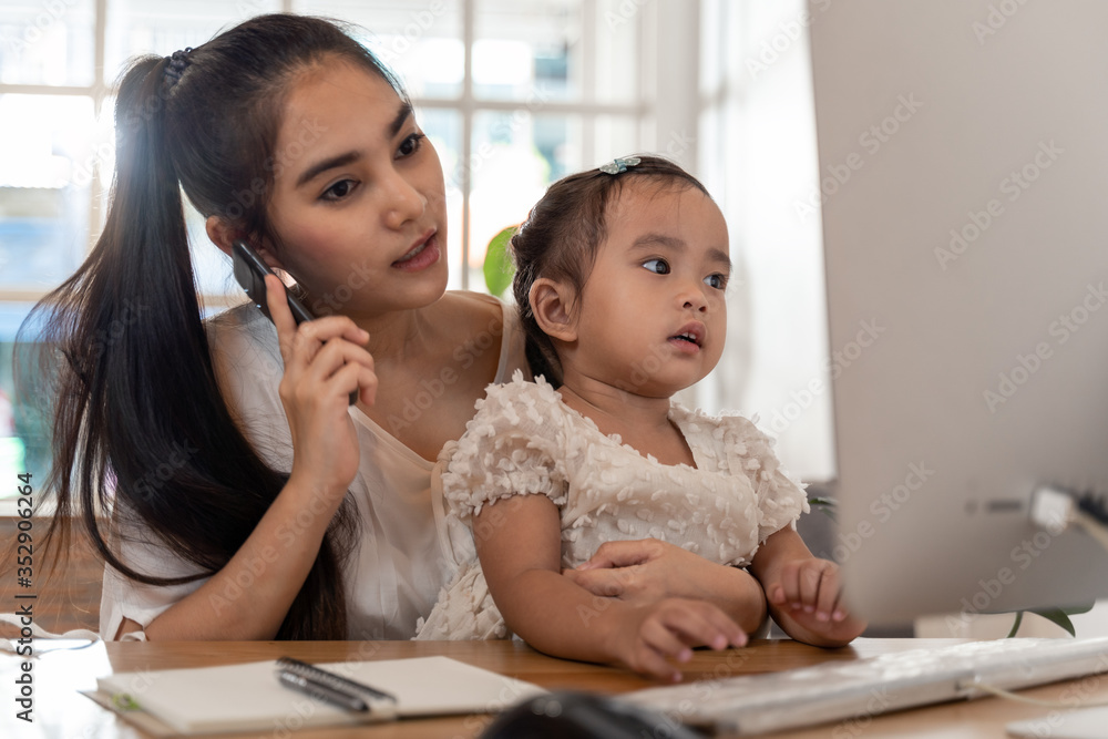 Work from home concept. Mother and daughter using a computer and internet during mother working from home Work from home concept. Mother and daughter using a computer and internet during mother working from home