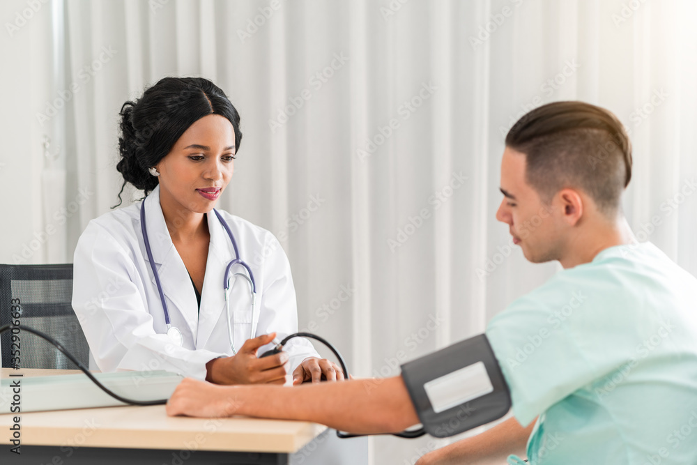The african american doctor is measuring blood pressure for the patient. And provide consultation regarding treatment to patients sitting in a wheelchair and closely monitor The african american doctor is measuring blood pressure for the patient. And provide consultation regarding treatment to patients sitting in a wheelchair and closely monitor