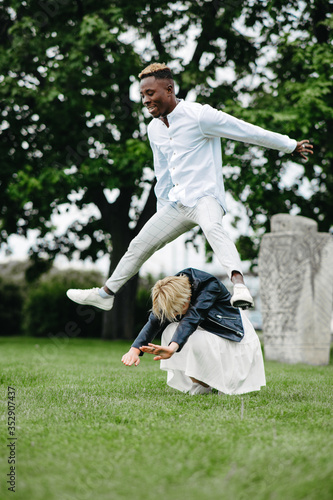 Interracial couple has fun, plays and jumps in park. photo