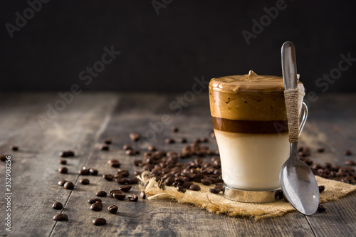 Creamy iced dalgona coffee on wooden table. Copy space	