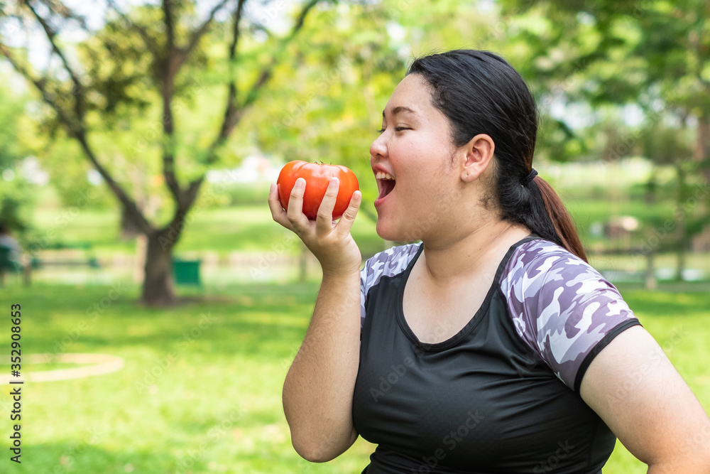Portrait of young Asian Fat woman holding red tomato on nature park background concept of healthy eating. Portrait of young Asian Fat woman holding red tomato on nature park background concept of healthy eating.