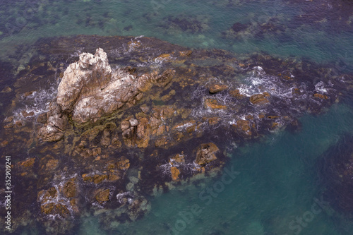 Sea water runs a wave on coastal stones and breaks against them. © Valerii
