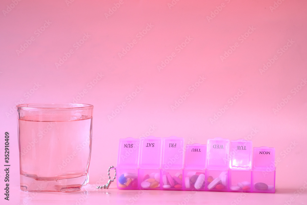 pill box and water glass on pink pill box and water glass on pink