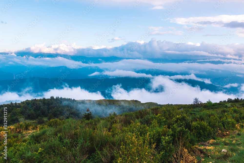 Fototapeta premium A picturesque wide landscape view of the French Alps mountains covered in clouds in the evening (Col de Rigaudon, Alpes-Maritimes, France)