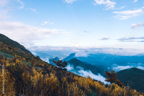 A picturesque wide landscape view of the French Alps mountains covered in clouds in the evening (Col de Rigaudon, Alpes-Maritimes, France)