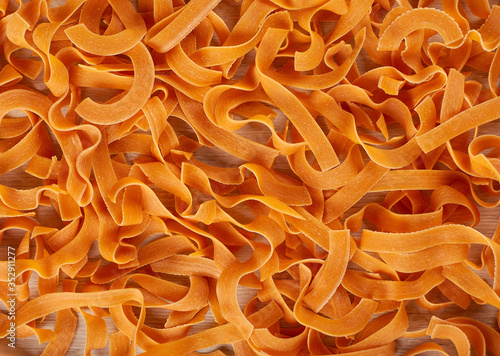 Orange pasta, dry pasta with tomatoes background