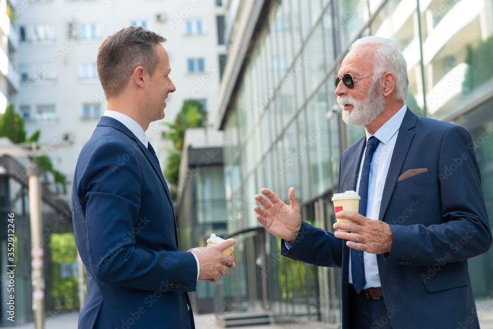 Young businessman discussing something positive with his mature colleague