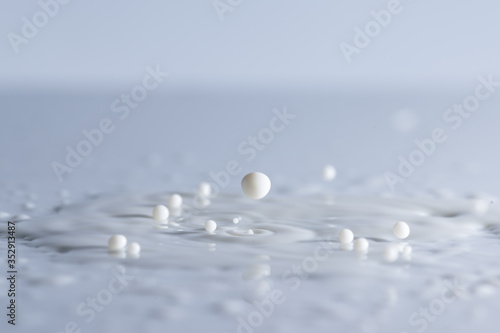 Milk drops splash and circle reflextion background.Pouring fresh milk drops falling into the the table.