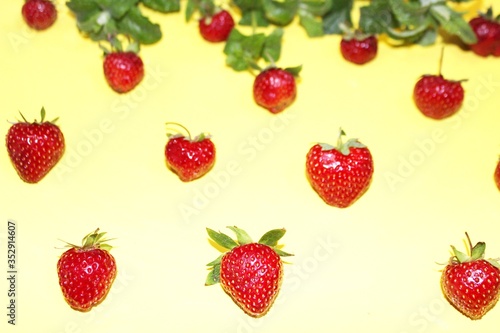 Obraz na płótnie Strawberry berries with mint isolated on a yellow background. Strawberries and mint leaves on a bright yellow background. Background for the design of banners, websites, blogs. Copy space. Red berries w salonie