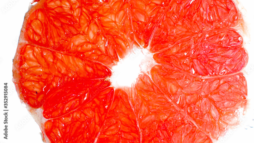 Closeup photo of grapefruit juicy slice over white background. Abstract background of exotic tropical fruits and berries Closeup photo of grapefruit juicy slice over white background. Abstract background of exotic tropical fruits and berries