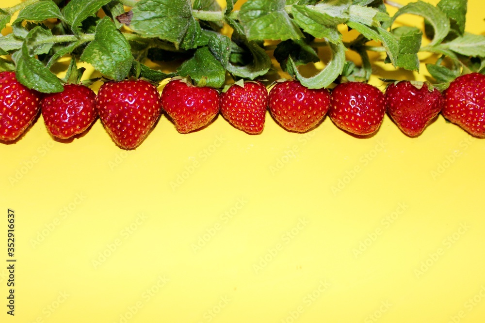 Strawberry berries with mint isolated on a yellow background. Strawberries and mint leaves on a bright yellow background. Background for the design of banners, websites, blogs. Copy space. Red berries