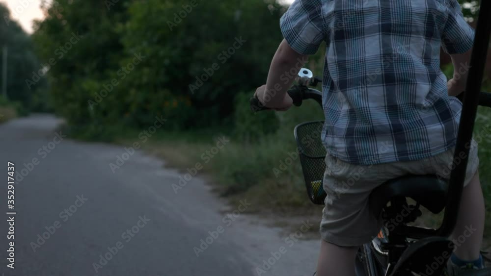 Little Boy Learns Riding Children's Bike with Assisting Young Mother Strolling on Rural Road. Summer Evening. 2x Slow motion - Half speed 60 FPS Little Boy Learns Riding Children's Bike with Assisting Young Mother Strolling on Rural Road. Summer Evening. 2x Slow motion - Half speed 60 FPS