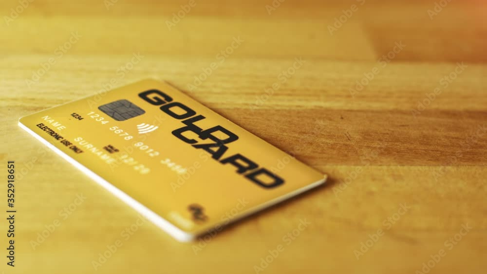 Customer or banker throwing a Gold credit card on a wooden counter for shopping. Bank, web, shopping concept. Financial transactions, online shopping, banking, plastic card, money. Customer or banker throwing a Gold credit card on a wooden counter for shopping. Bank, web, shopping concept. Financial transactions, online shopping, banking, plastic card, money.