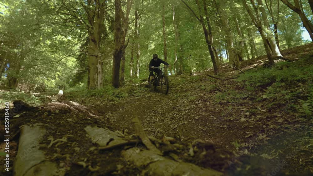 Amazing shot of a biker with MTB E-bike biking down the hill in the forest. Extreme rider brakes and sends rocks flying directly to the camera. Amazing shot of a biker with MTB E-bike biking down the hill in the forest. Extreme rider brakes and sends rocks flying directly to the camera.