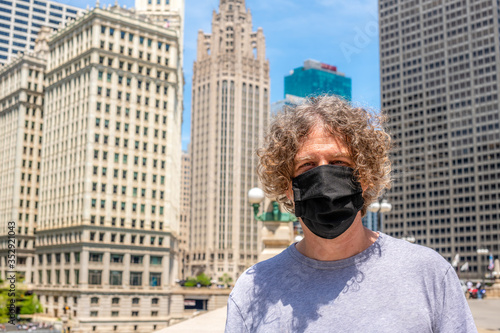 A man wears a black cloth mask while out for a walk downtown in Chicago.