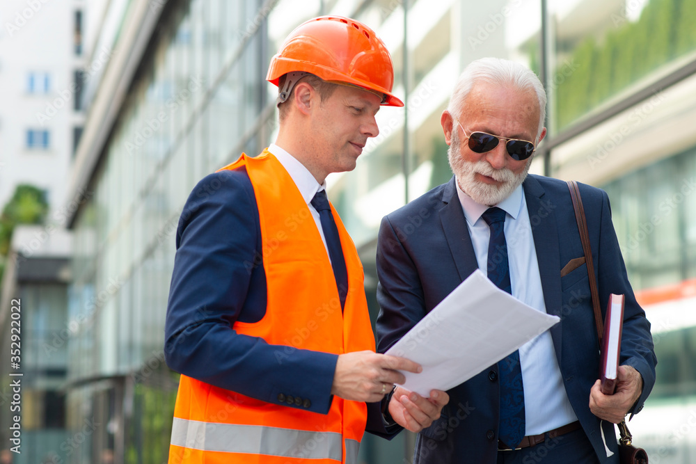 Engineer man showing papers to business man